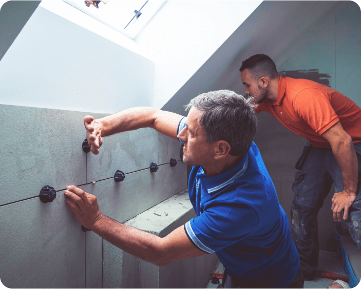 Two workers installing tiles in a bright attic space